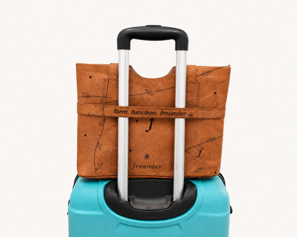 Canopy Work Tote resting on a suitcase with its luggage strap around the telescopic handle.