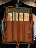 Cadence Stick and Mallet Bag opened beside a drum kit, with drumsticks arranged in the divided interior pockets.