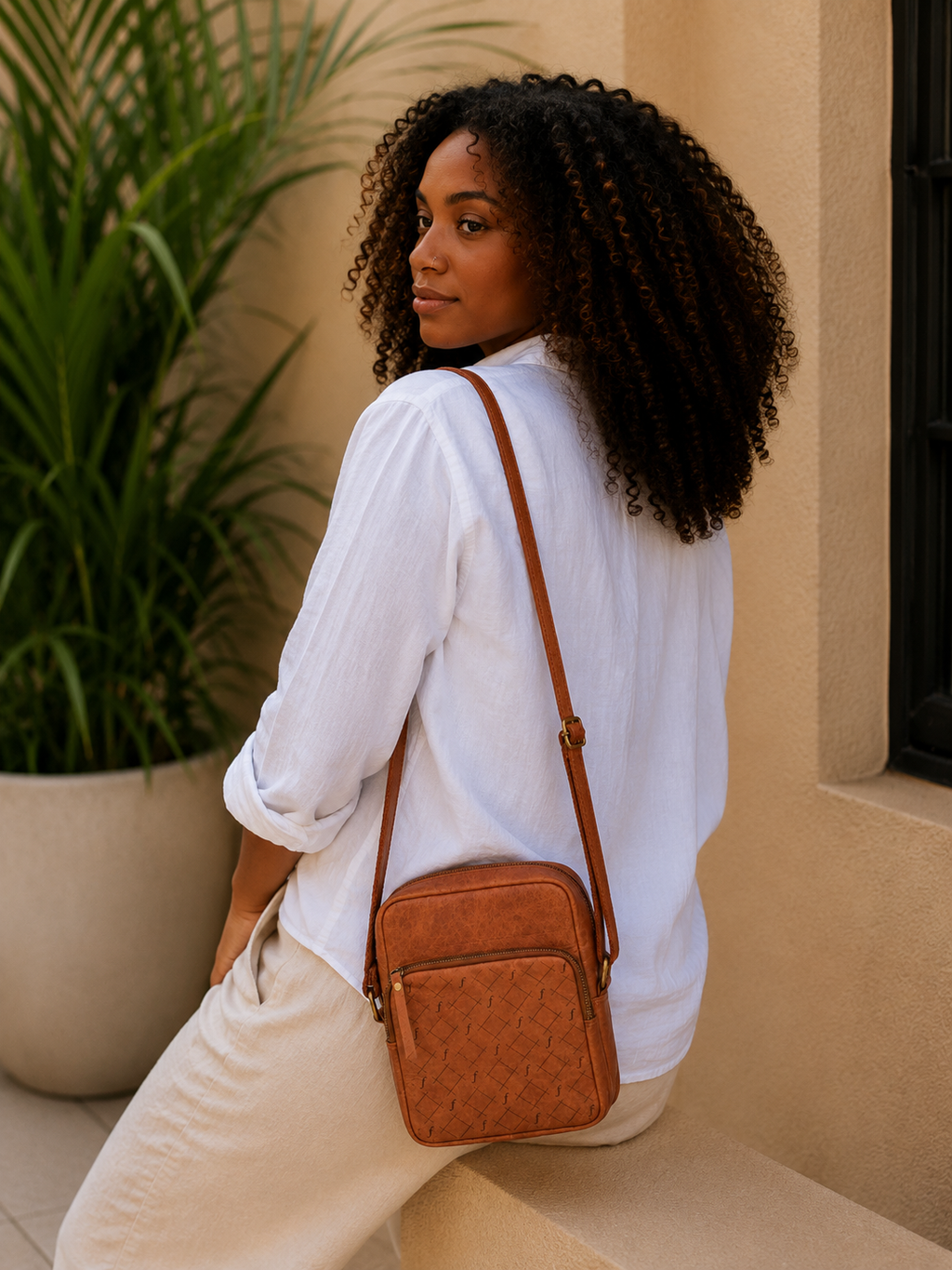 Bracken Mini Crossbody carried over one shoulder by a seated wearer.