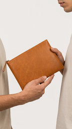 Twinleaf and Clay pouch held between two people, showing its flat shape and zipped top.