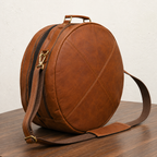Woodnote Drum Bag viewed at an angle, showing its circular shape, stitched front panels, top handle and clip-on shoulder strap.